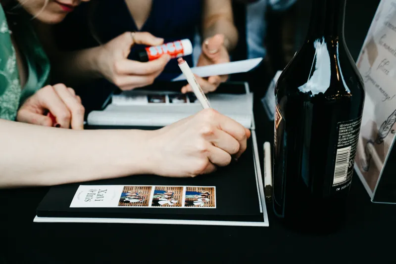 Invitados firmando el álbum junto a las tiras de fotos impresas